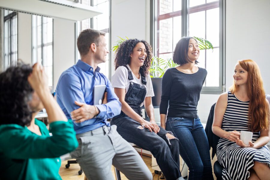 Cheerful multi-ethnic business colleagues in meeting. Male and female professionals laughing during a meeting.